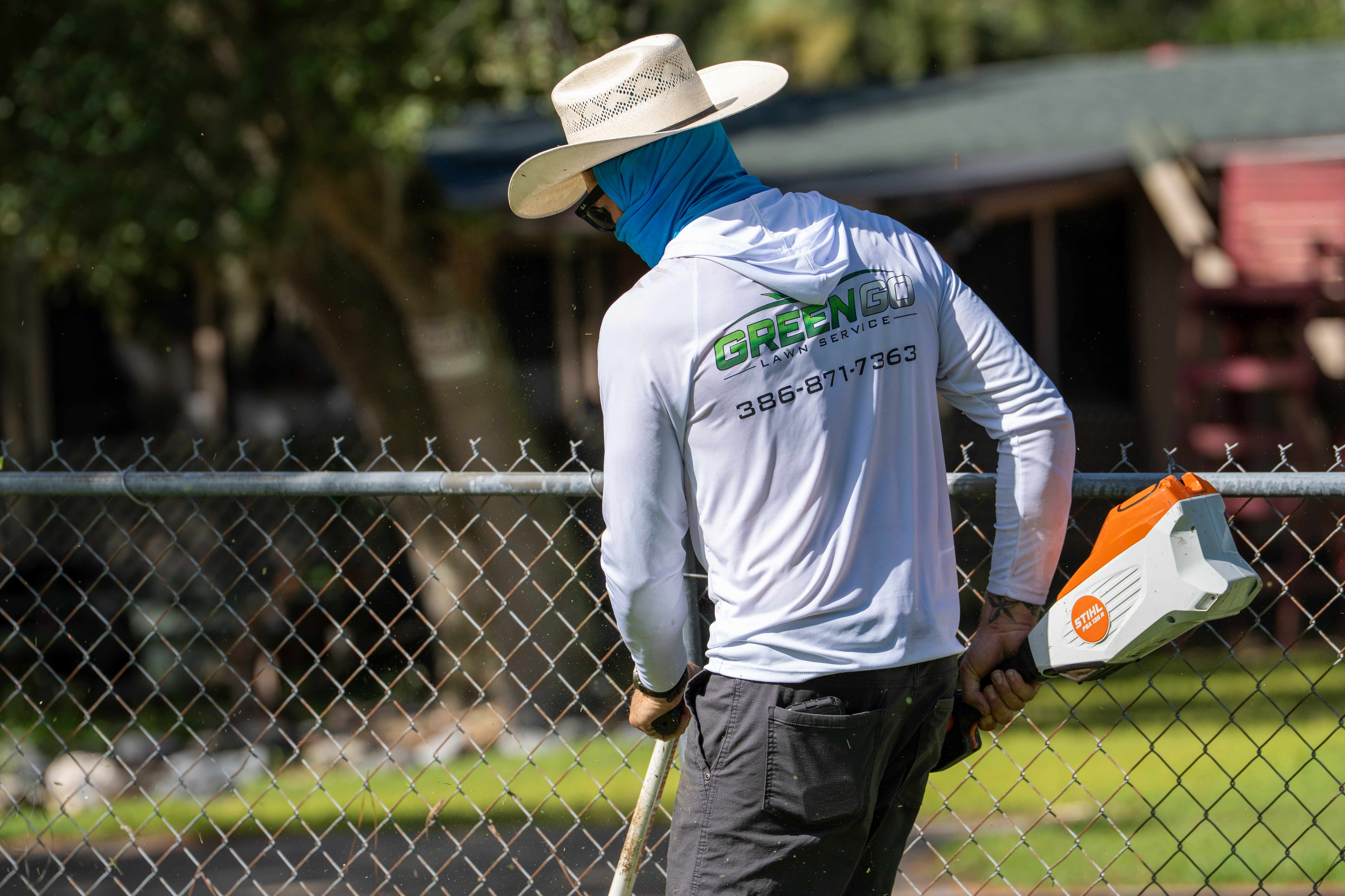 Landscaper trimming shrubs in a tidy Florida landscape bed